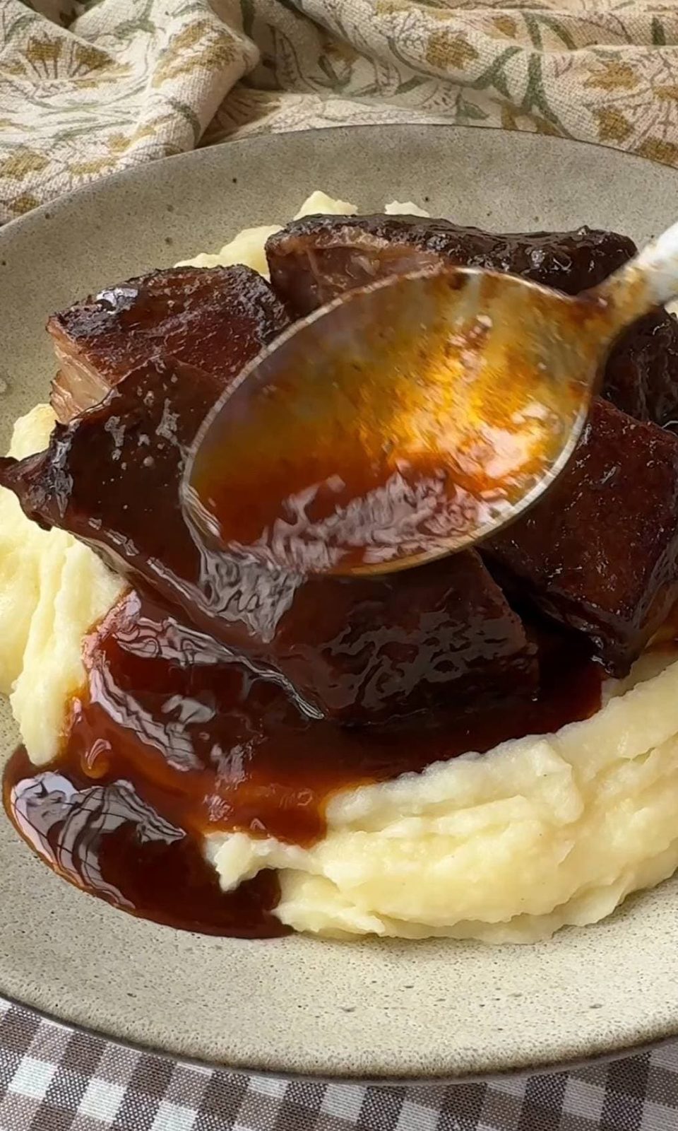 Pouring red wine sauce over braised short ribs before serving.