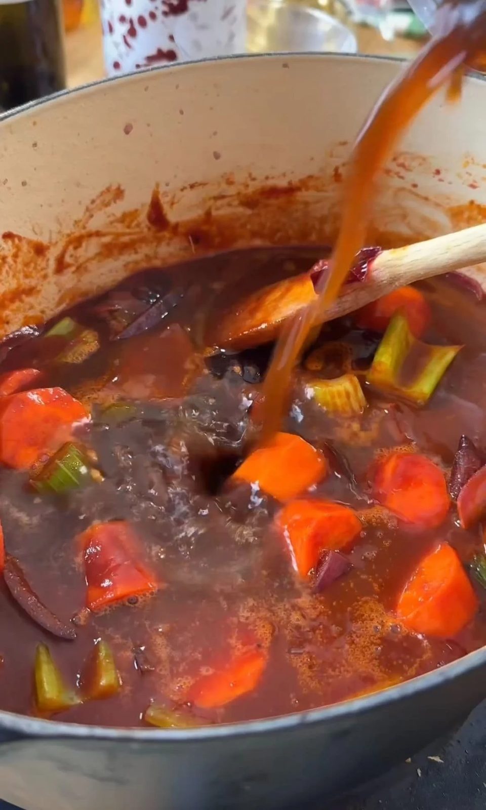 Adding beef stock to short ribs before braising.