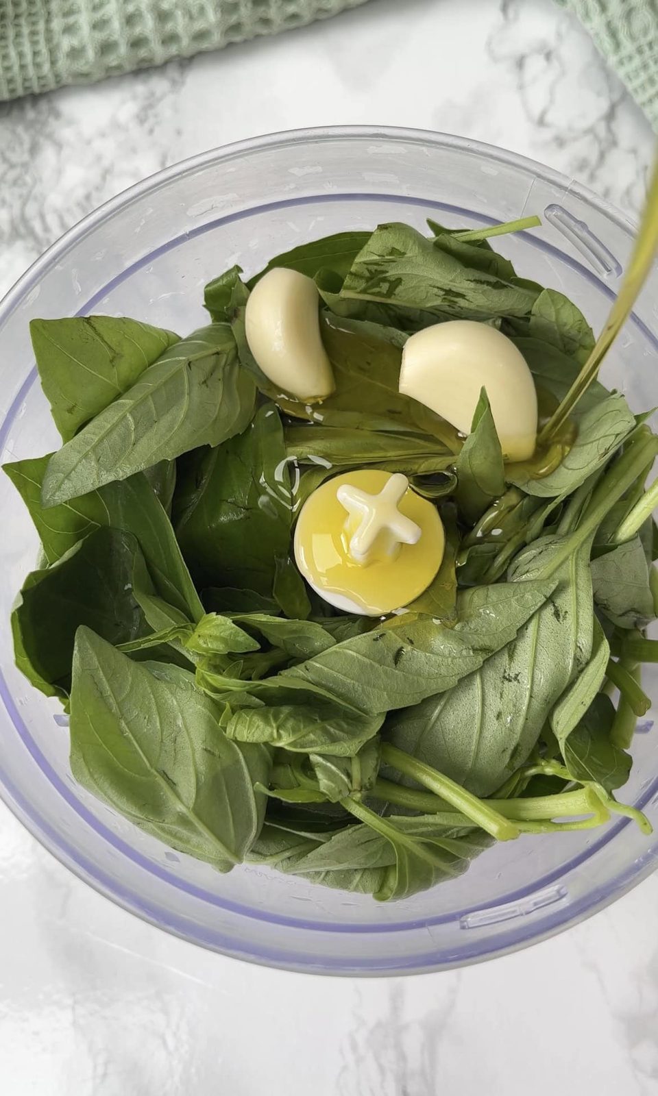 adding basil to a blender for pesto.