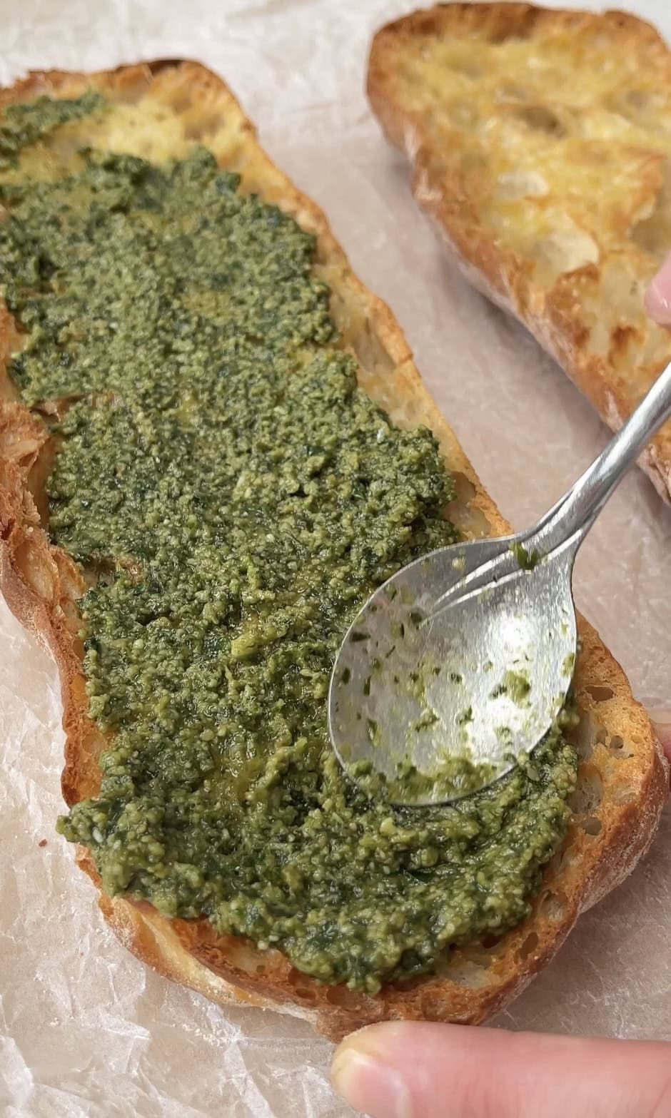 adding pesto to caprese bruschetta.