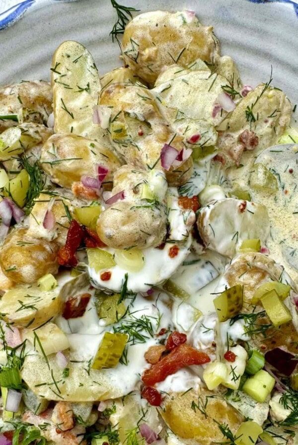 potato salad with dill and pickles in a bowl with spoon.