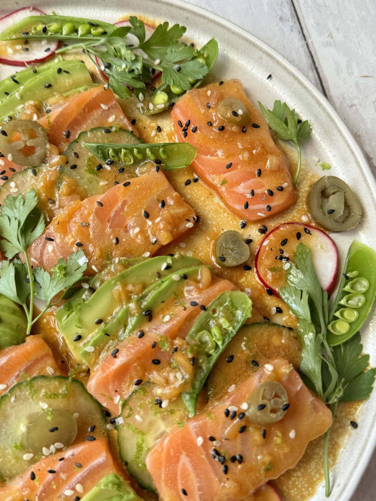 salmon crudo close up on a white plate.