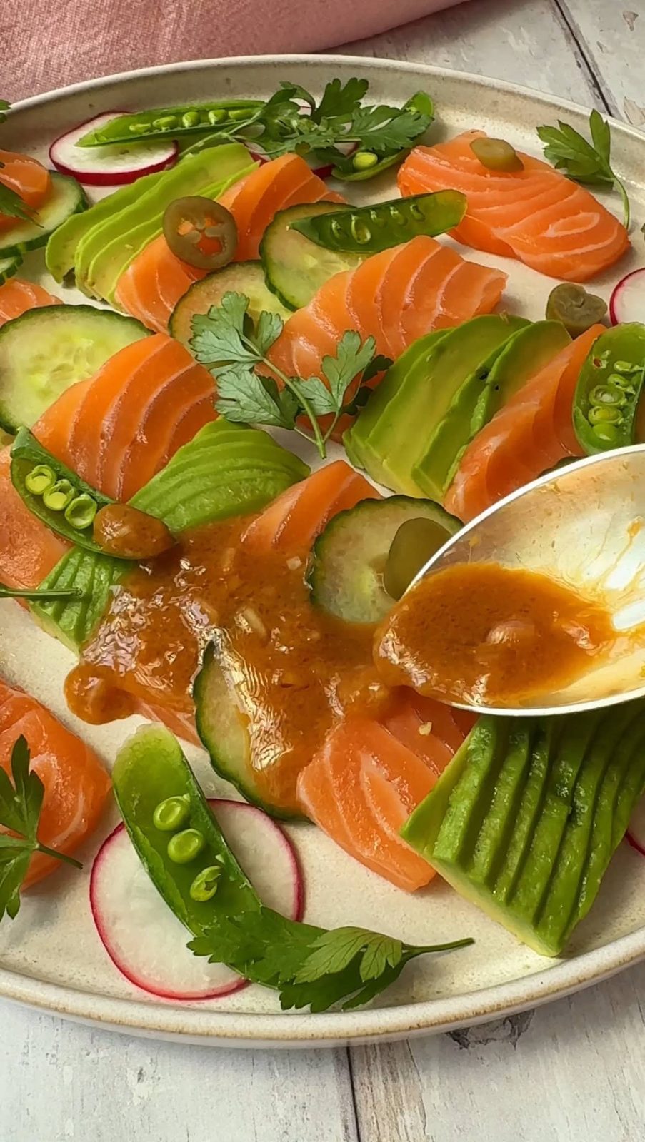 spooning dressing over salmon crudo.