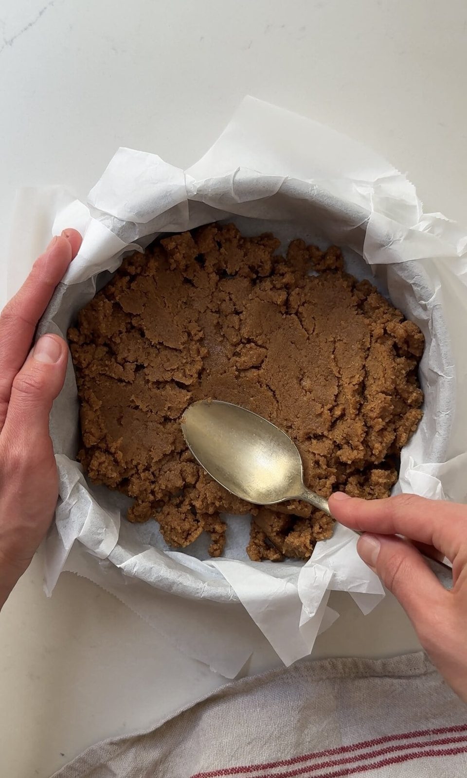 pressing the biscuit base into the tin.