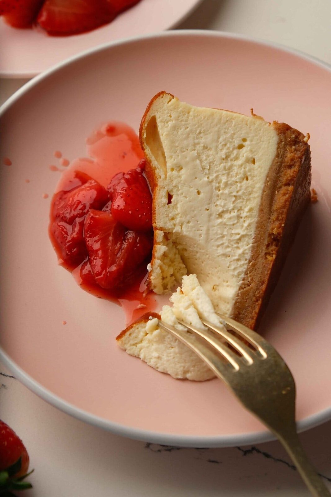 san sebastian cheesecake on a pink plate with strawberries.