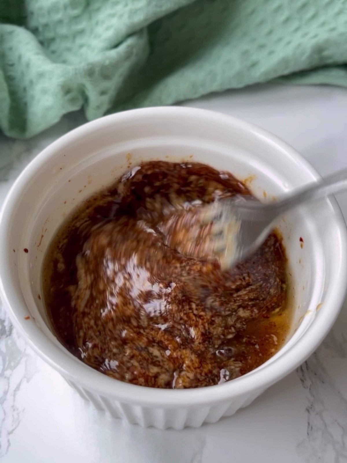 Mixing tahini salad dressing with other ingredients in small bowl.