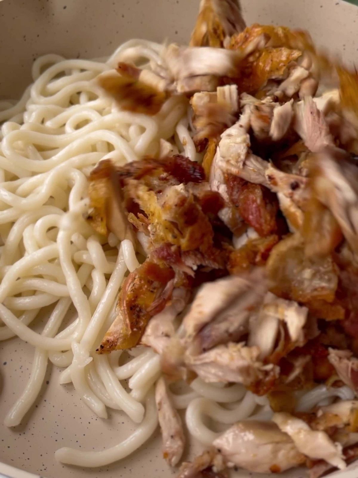 Mixing noodles, dressing, and chicken.