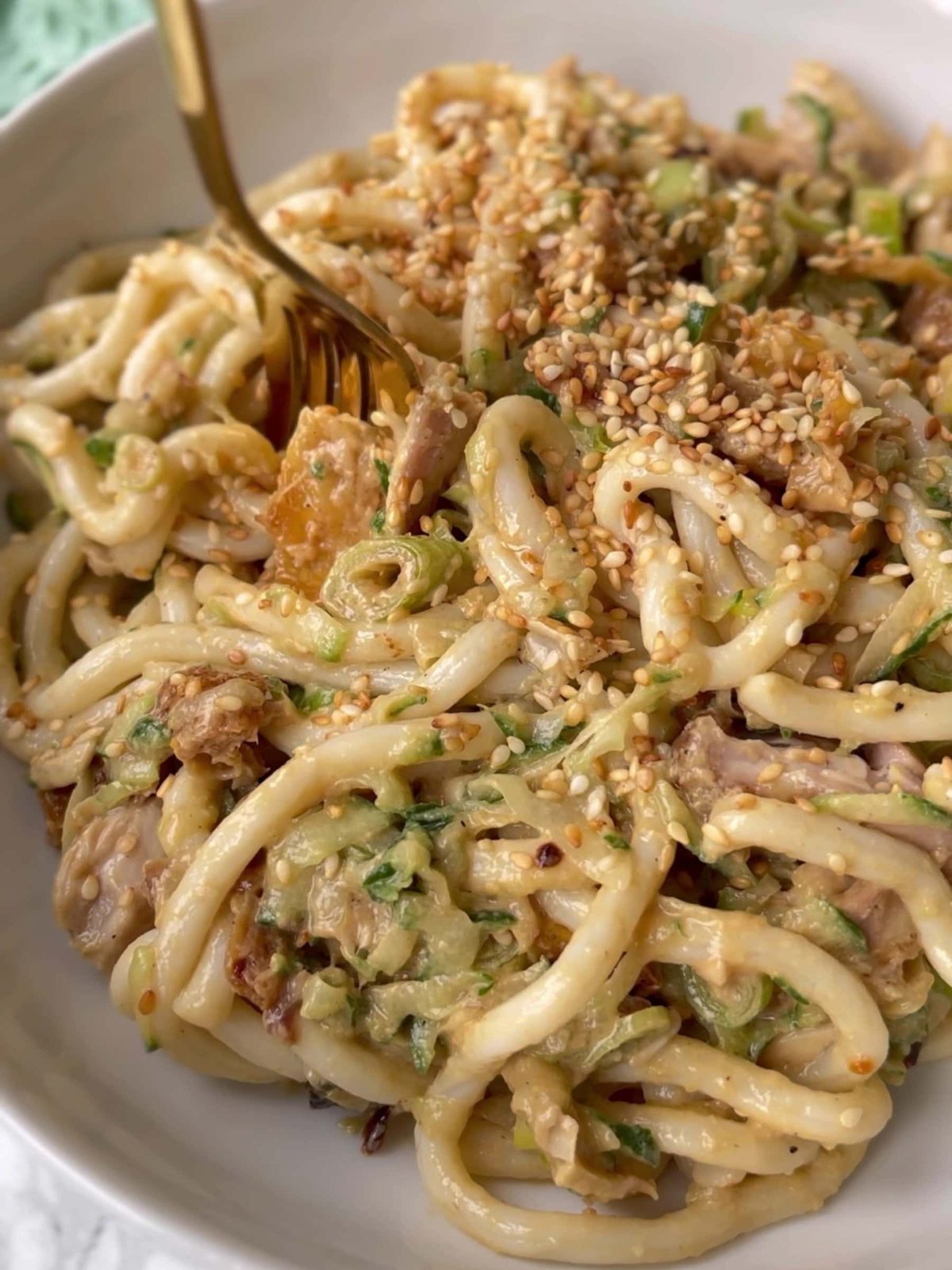 Cold chicken and udon noodle salad with sesame seeds in bowl.