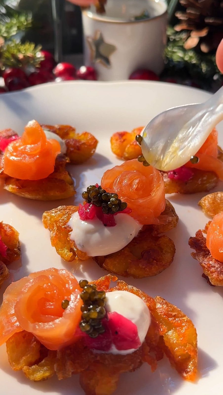 Smashed potatoes with creme fraiche, smoked salmon, and pickled red onion on plate.