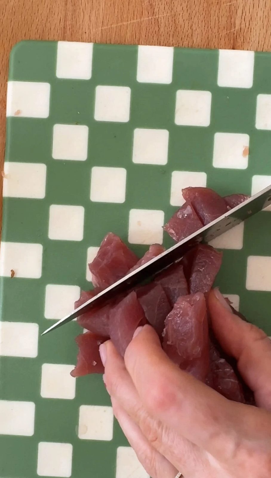 Dicing raw tuna with large knife.