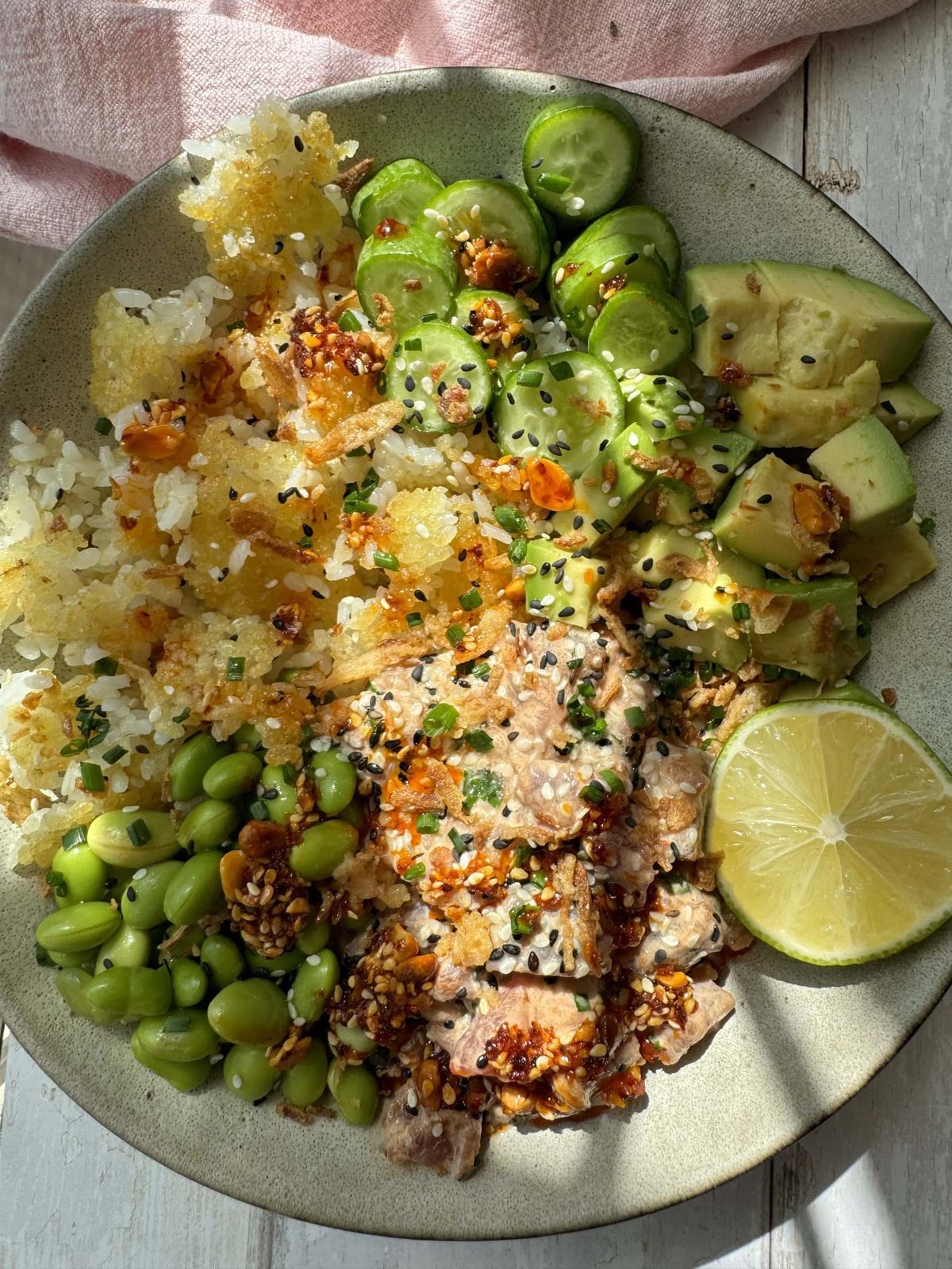 Spicy tuna in a bowl with crispy rice and cucumber and avocado.