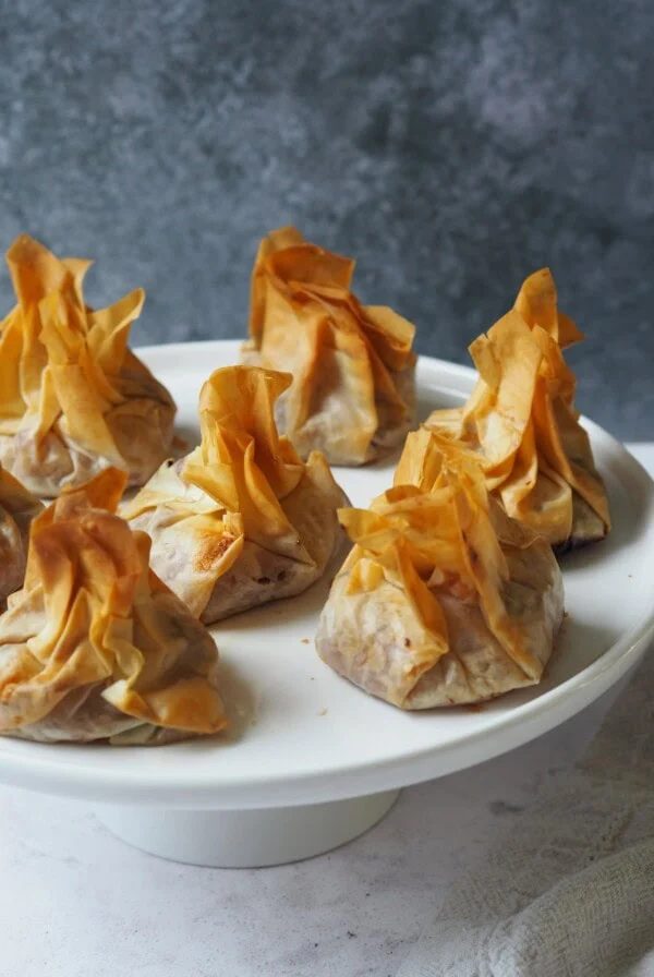 White serving platter of filo pastry parcels.