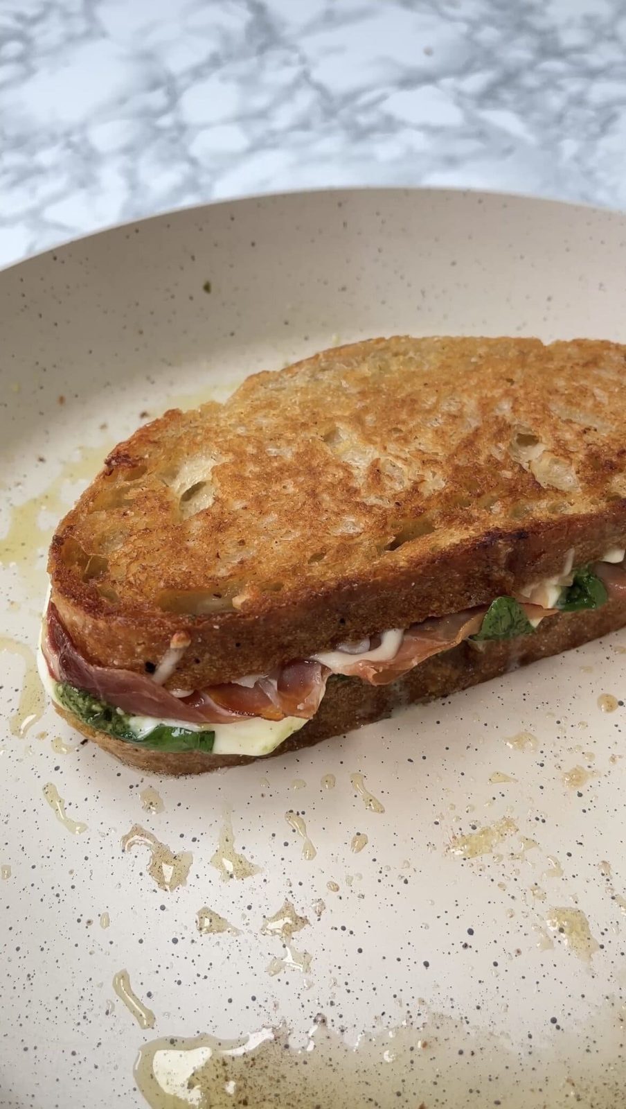 Toasted prosciutto and cheese sandwich on plate.