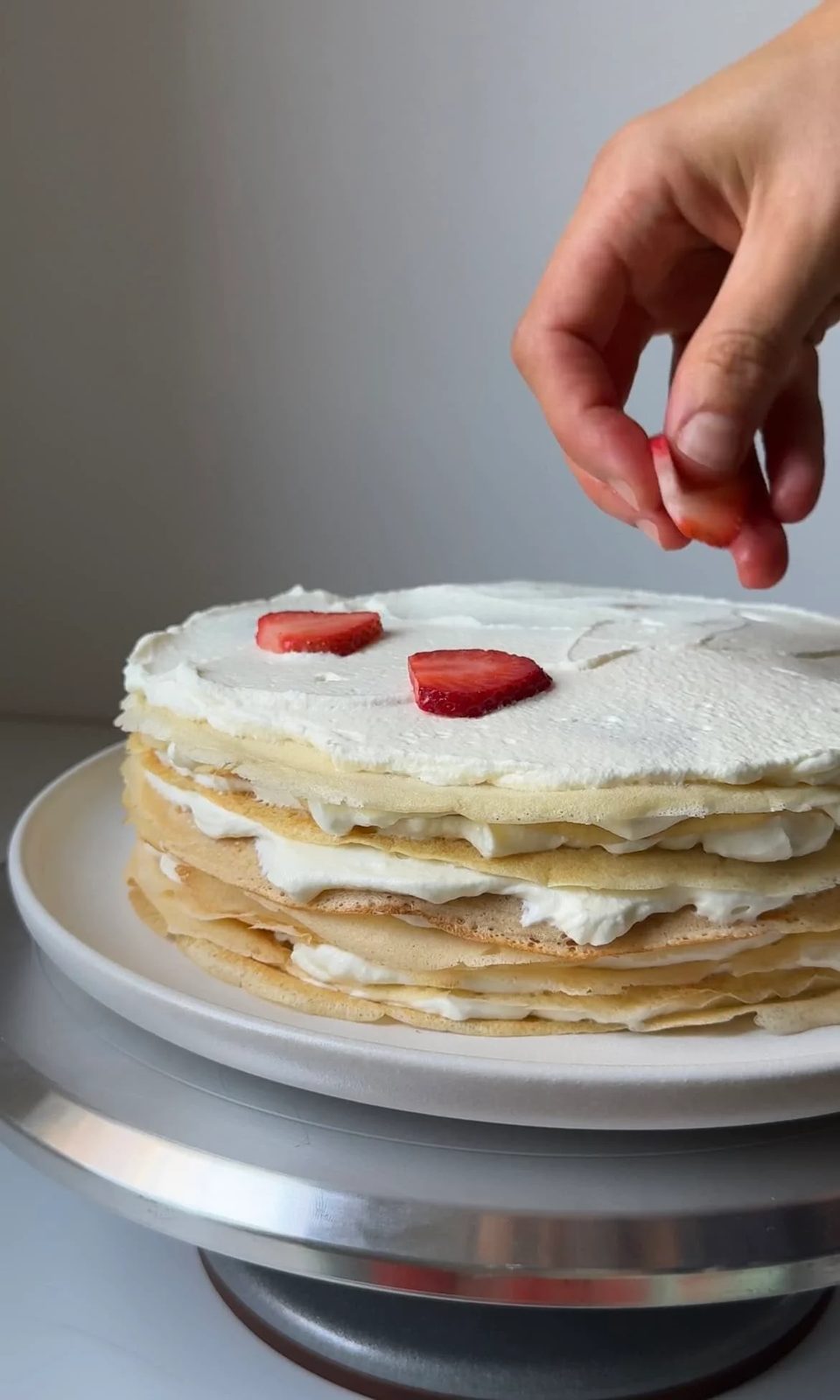 laying strawberries on mille crepe cake.