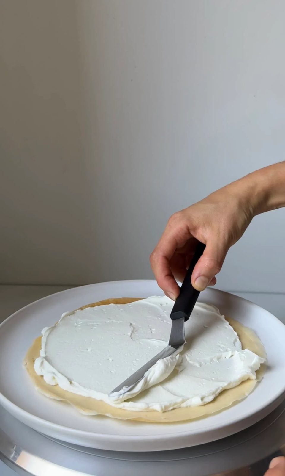 smoothing cream onto crepe layers.