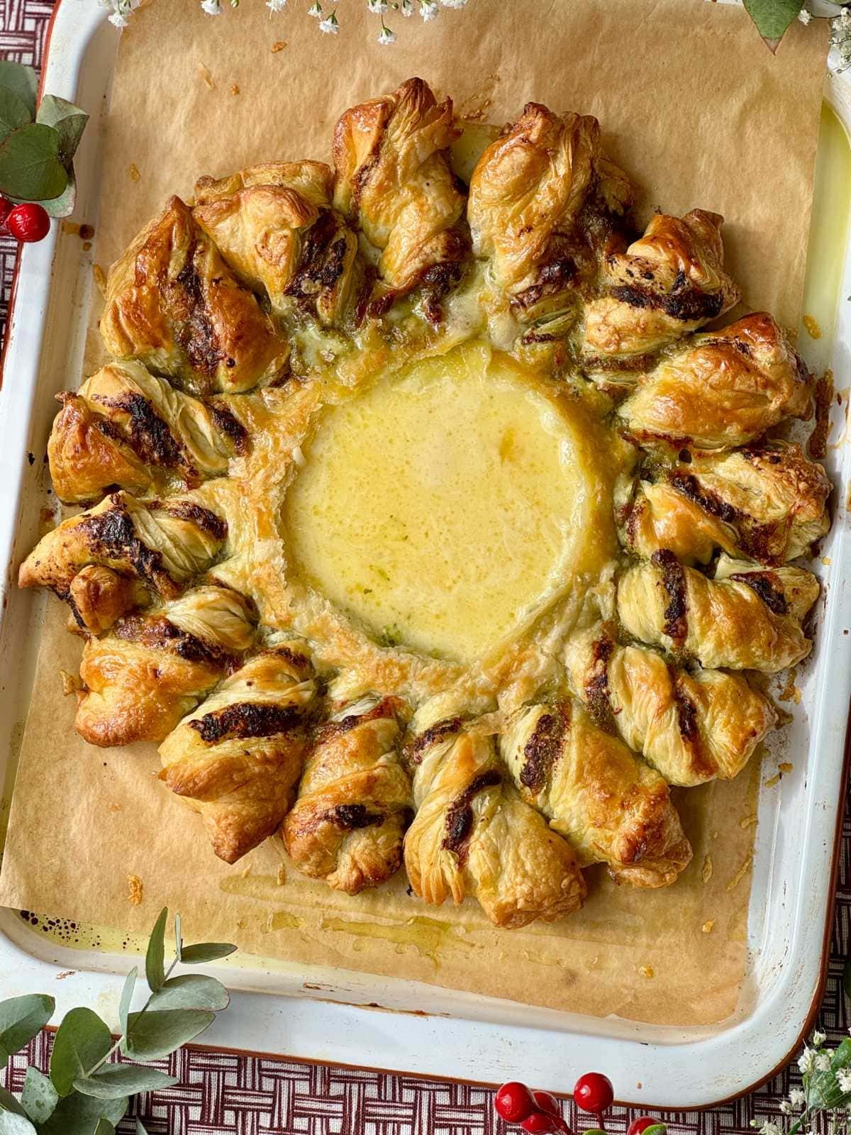 Tarte pesto soleil with melted Brie on parchment-lined baking sheet.