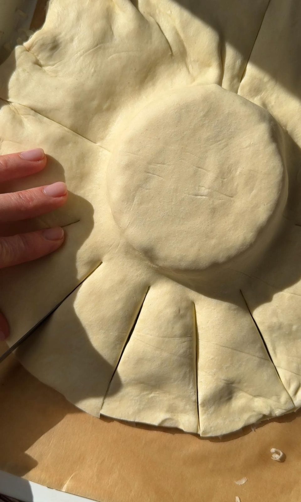 Cutting slits in puff pastry over Brie.