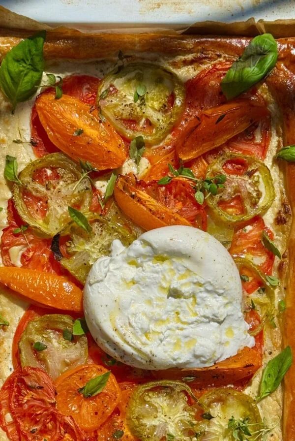 Tomato puff pastry tart with burrata on top in pan.