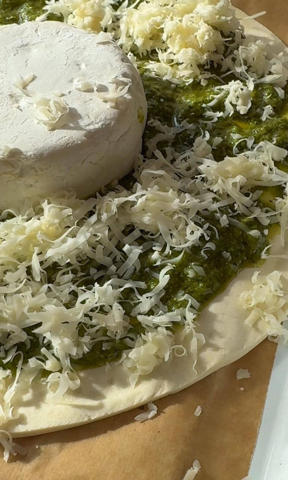Layering Brie and Comte on pesto-covered pastry.
