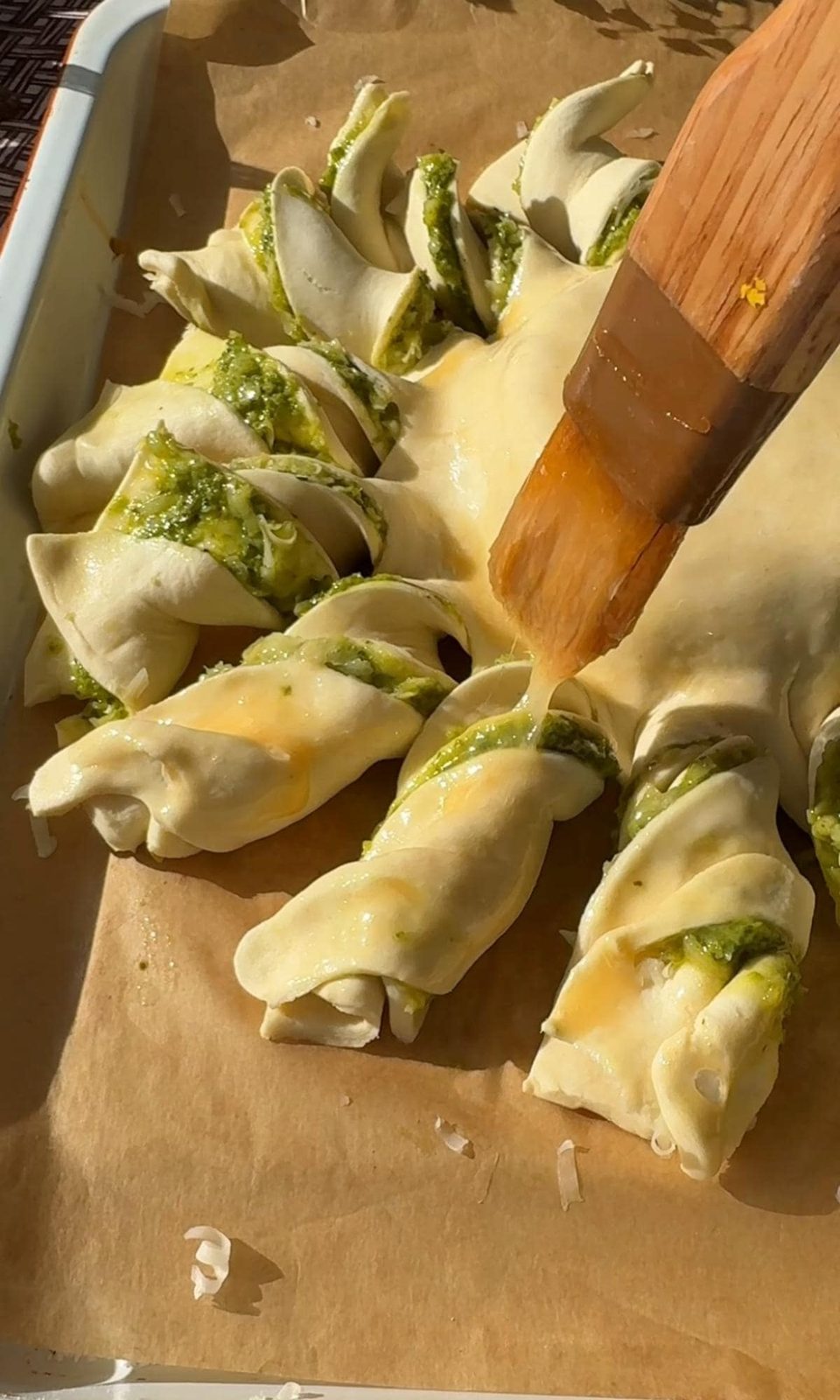 Adding egg wash over puff pastry twists.