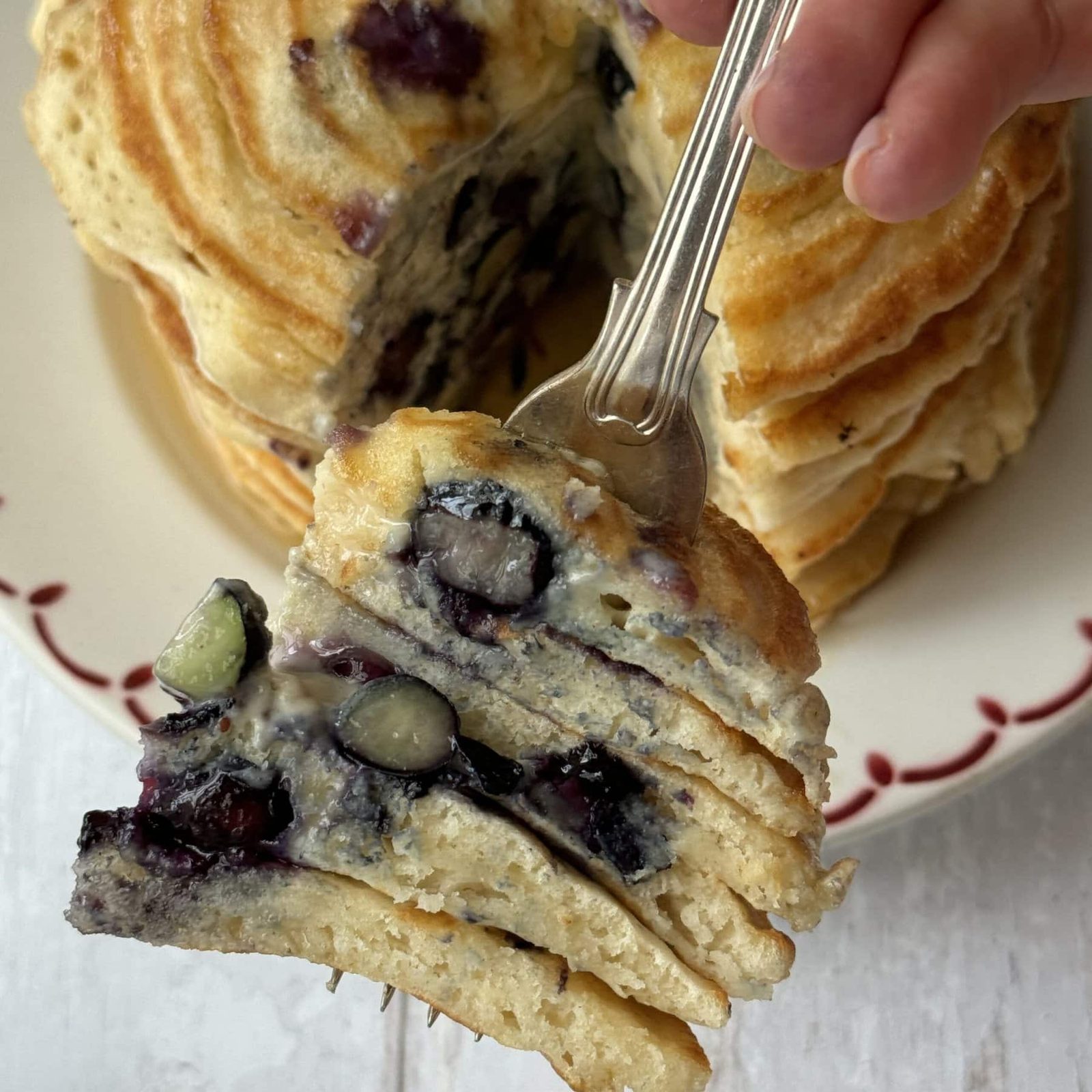 A forkful of pancakes with blueberries.
