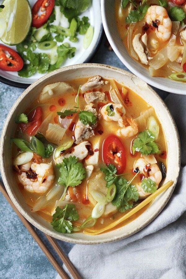 chicken tom yum soup in a white bowl with chilli and coriander on top.