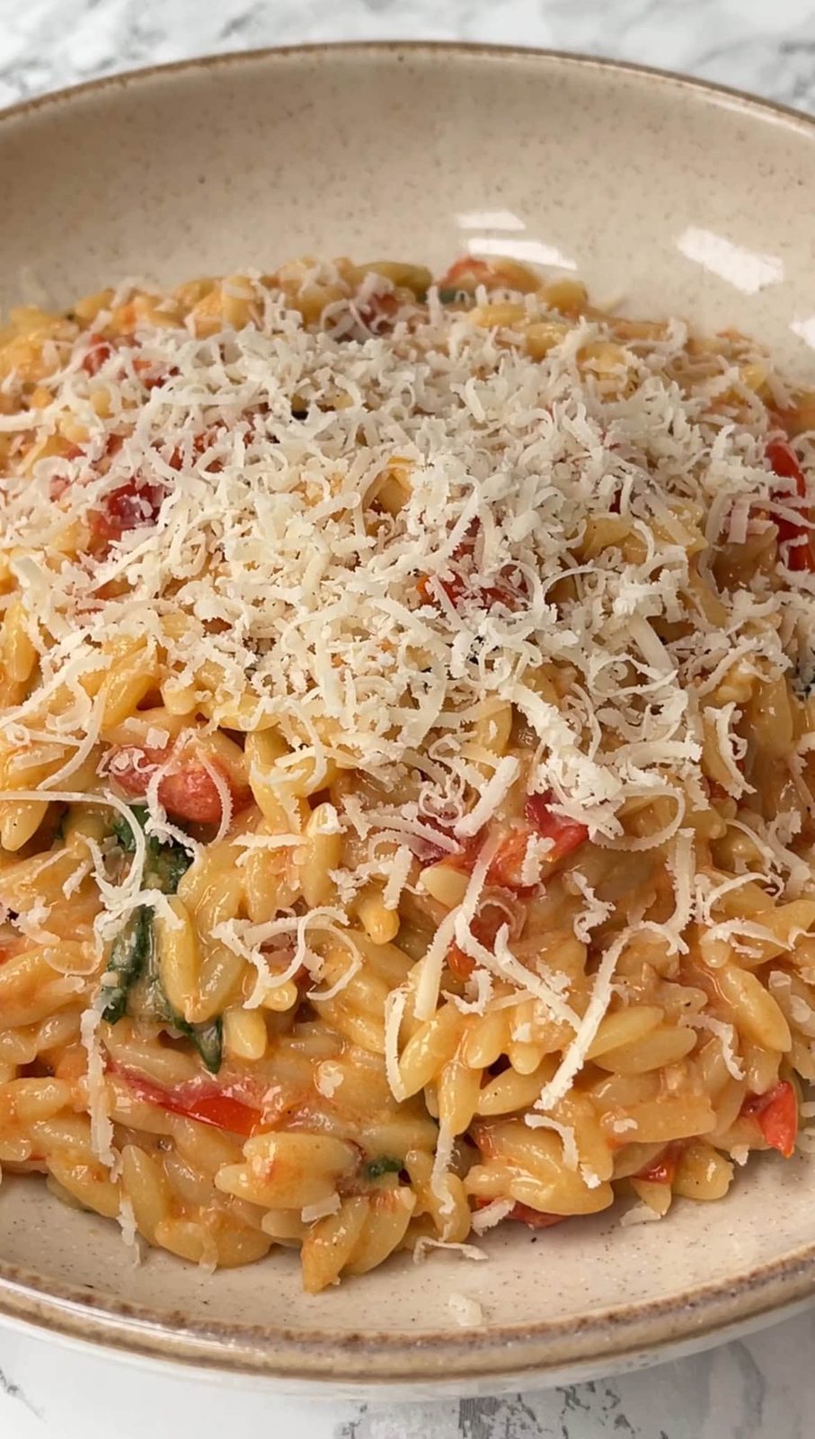 creamy orzo with tomato and mascasrpone in a beige bowl.