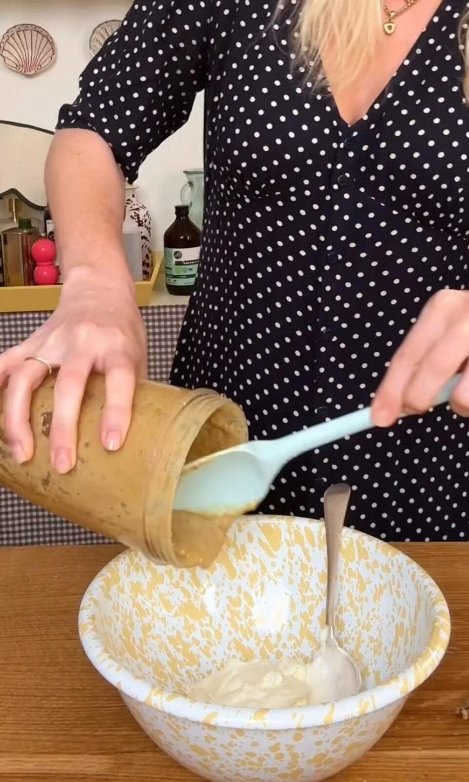 Pouring anchovy paste into creme fraiche with spatula.