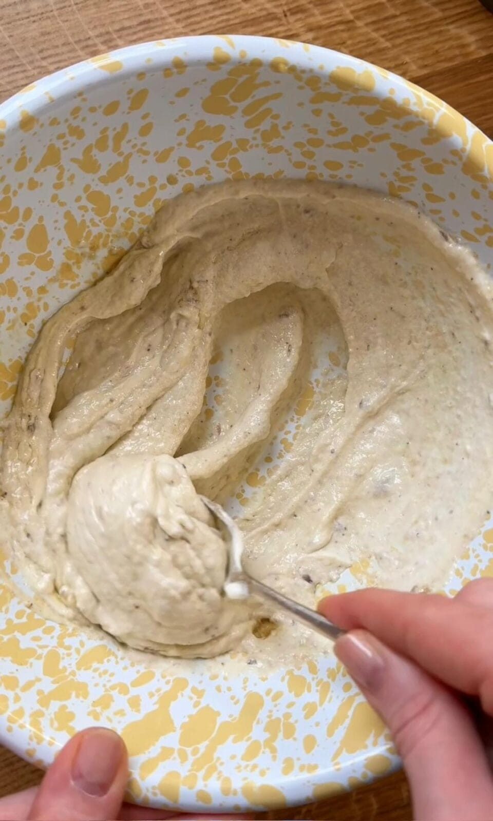 Mixing anchovy paste with crème fraîche in bowl with spoon.