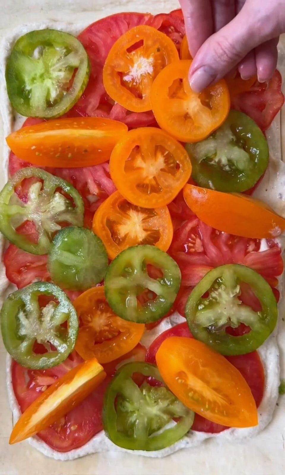 Laying heirloom tomatoes on puff pastry topped with anchovy crème fraîche.