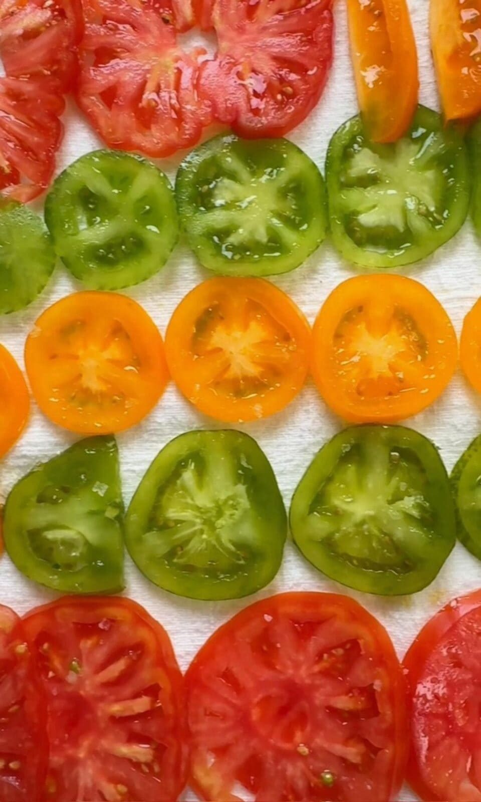 Variety of salted tomato slices on towel.