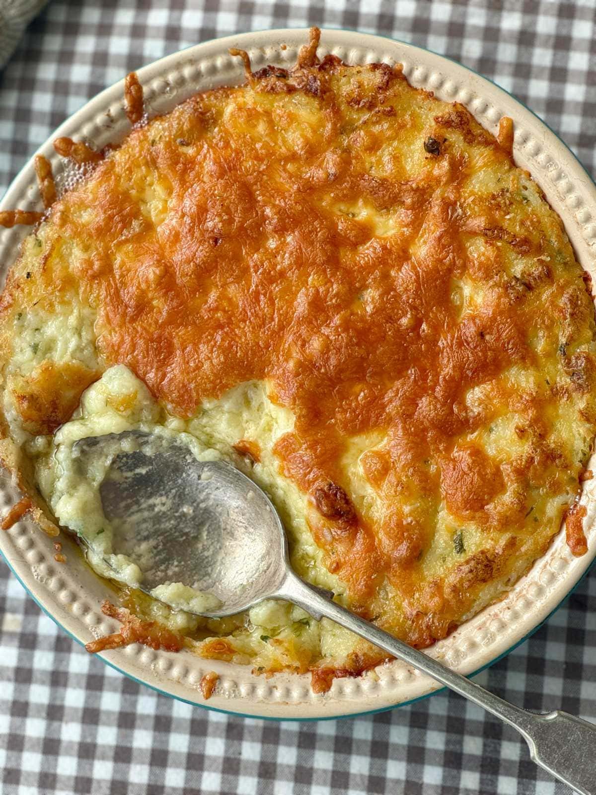twice baked mashed potatoes in a dish with cheese on top.