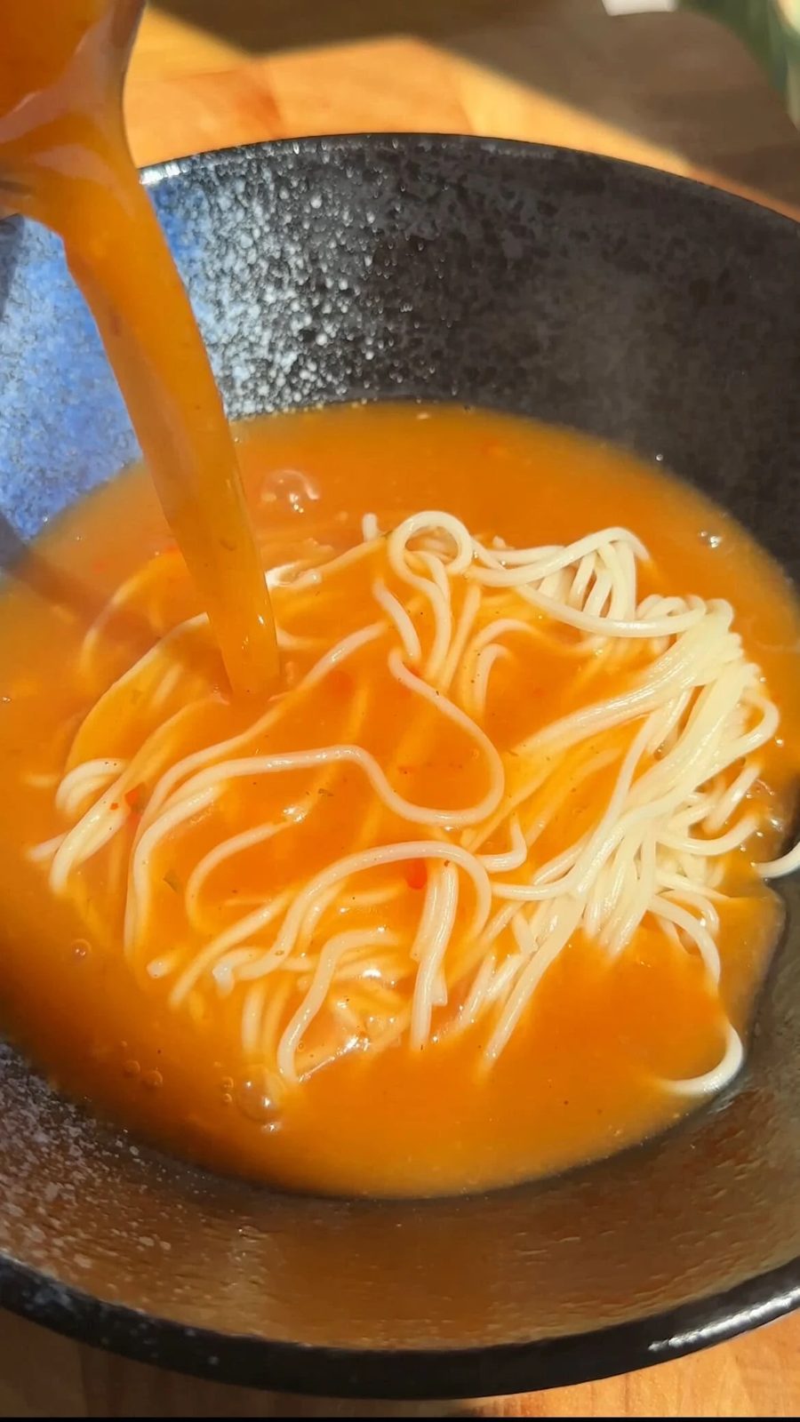 pouring broth over noodles