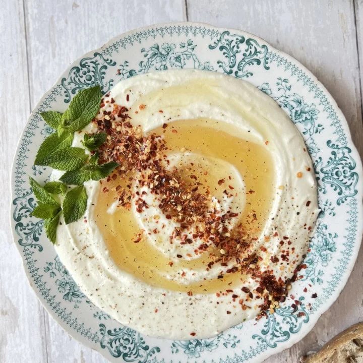 whipped ricotta cheese on a blue plate with honey and chilli flakes.