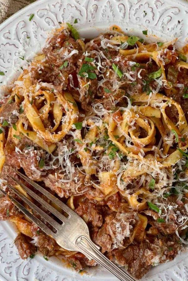 beef shin ragu with tagliatelle in a white bowl.