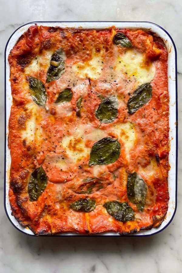 Baked courgette lasagne (zucchini lasagna) in a falconware baking dish topped with basil leaves.