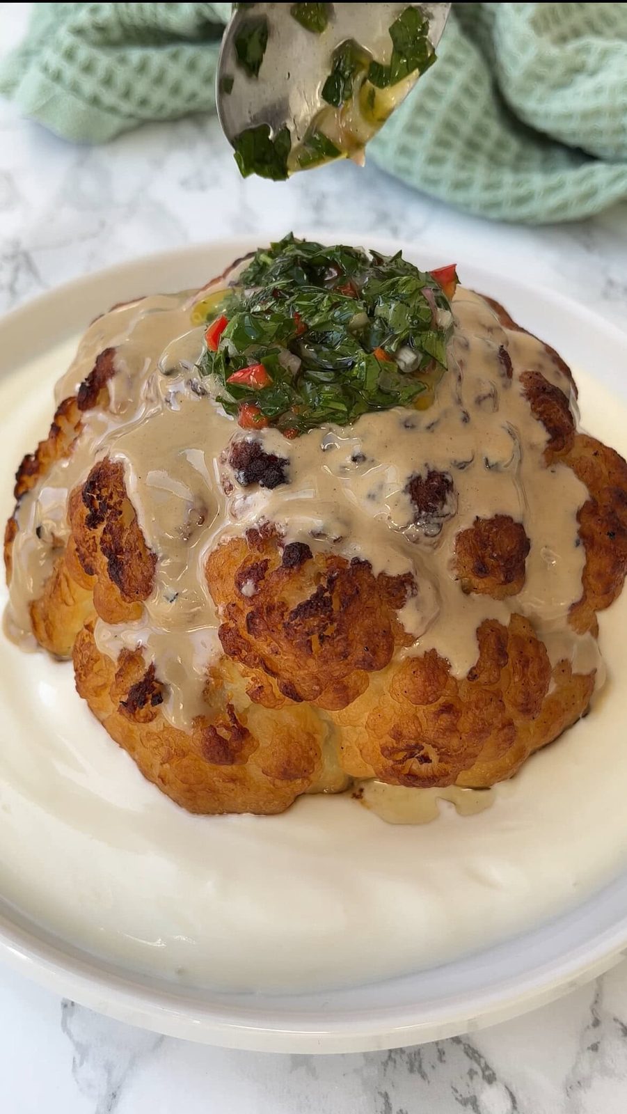 topping roasted cauliflower with tahini and chimichurri.