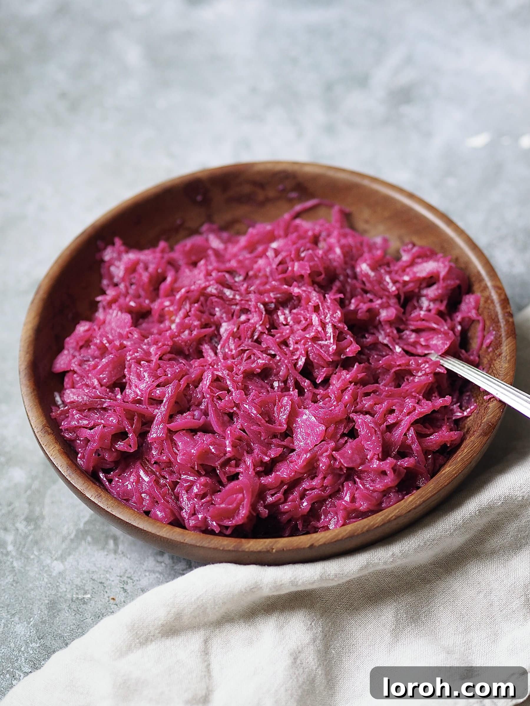 A wooden bowl overflowing with perfectly cooked and glistening sticky red cabbage.