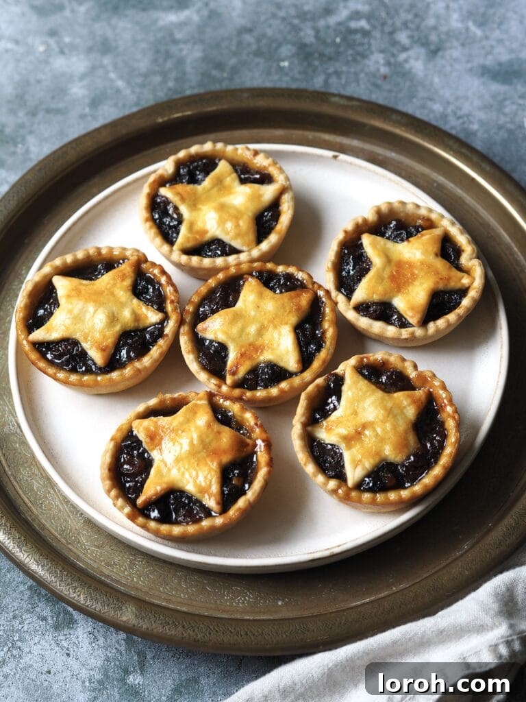 Plate of six mince pies topped with pastry stars, dusted with icing sugar.