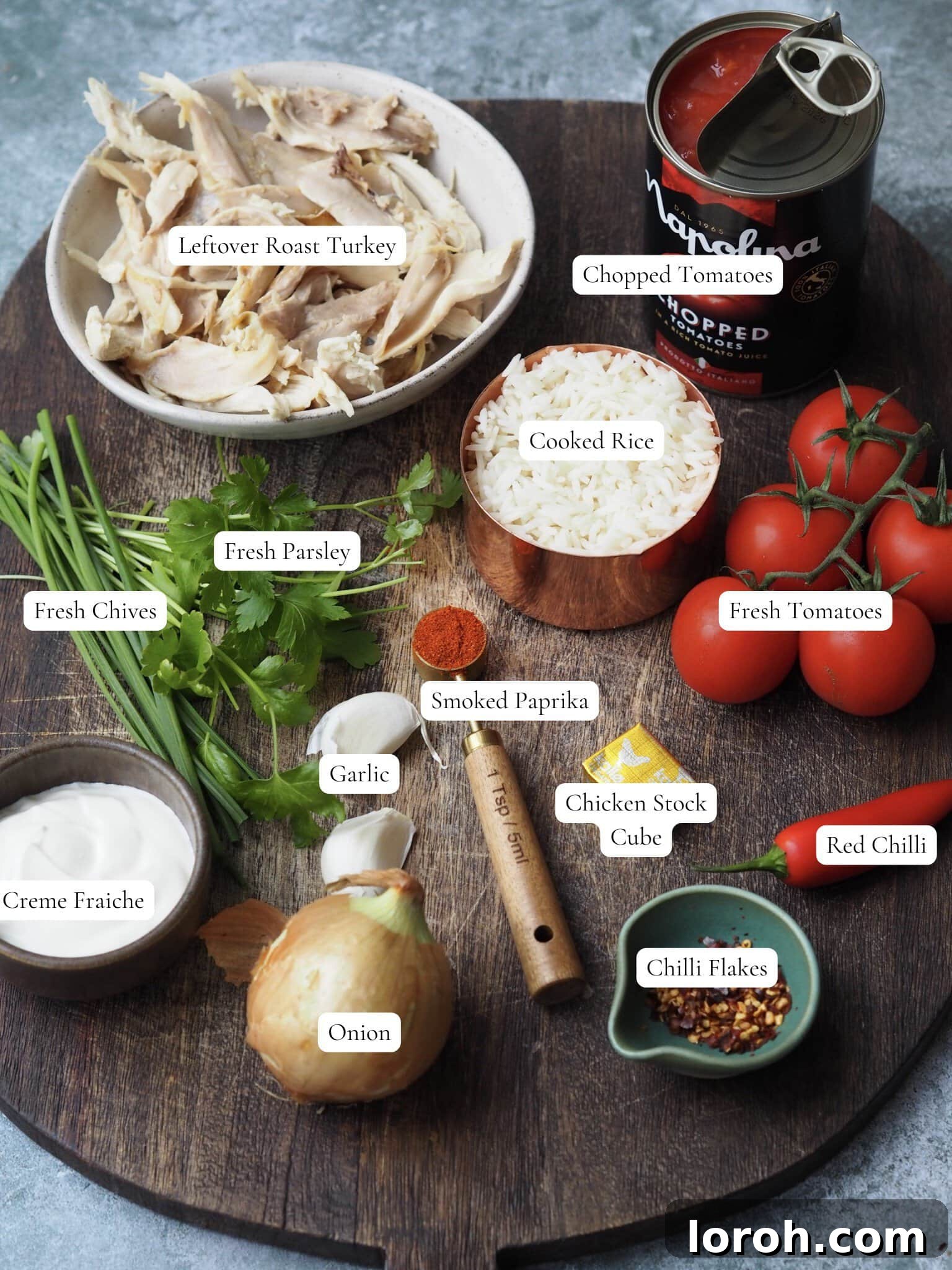 A flat lay image showcasing fresh ingredients for Turkey and Rice Soup, including tomatoes, garlic, onion, and herbs.