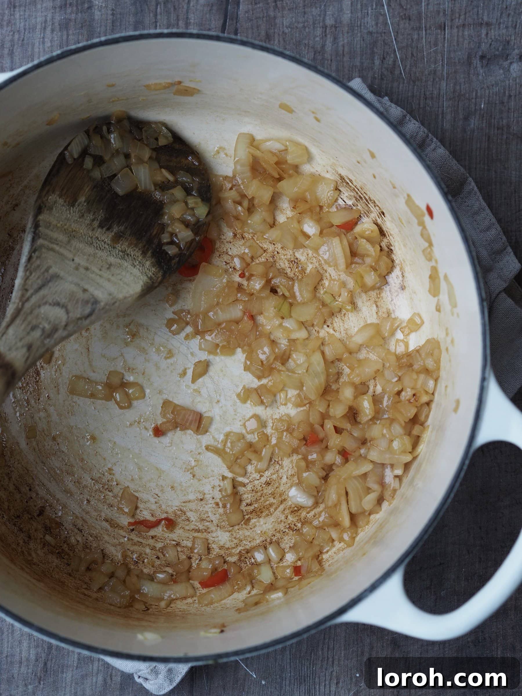 Sautéing finely chopped onions and chili in olive oil in a large pot, releasing their aromatic flavors.