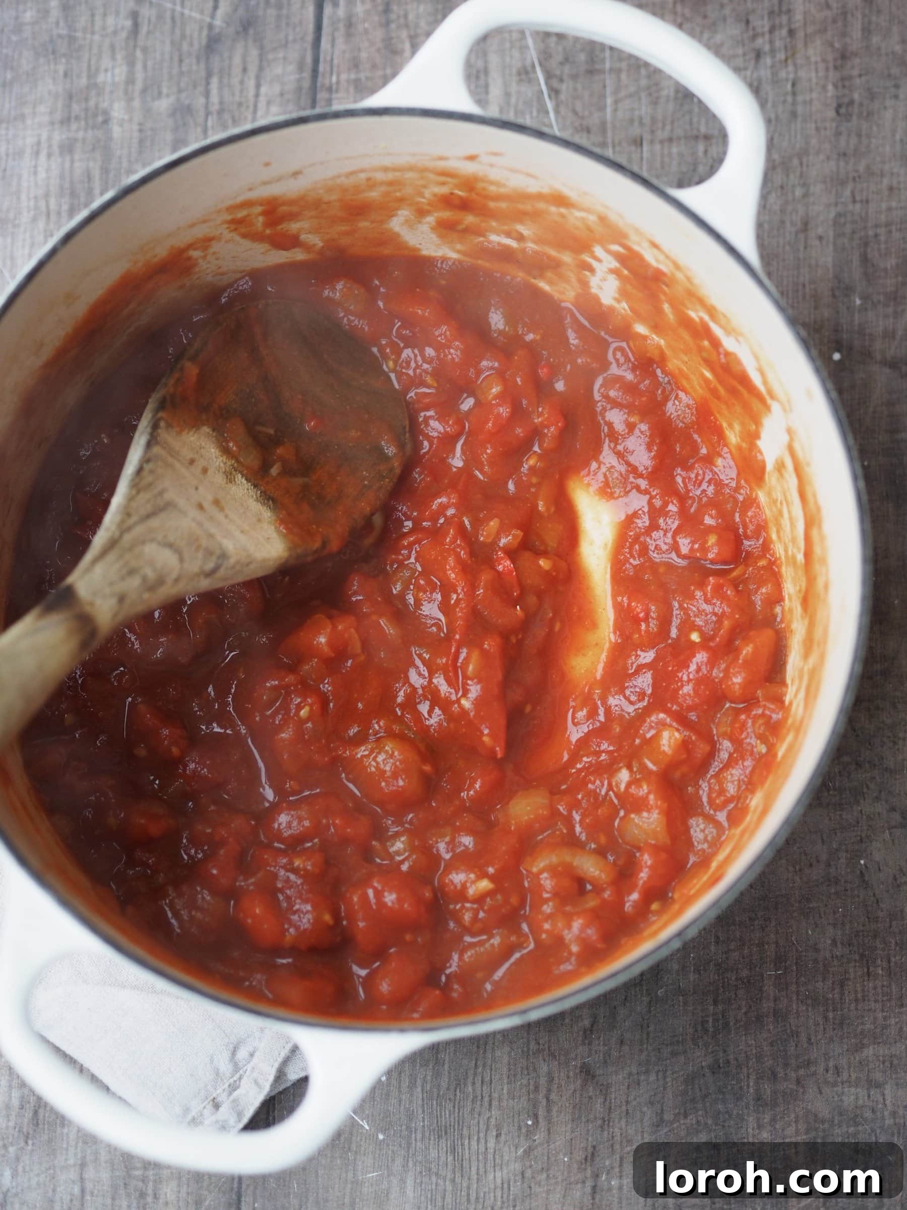 Simmering a rich tomato and spice base in a pot, creating a flavorful foundation for the soup.