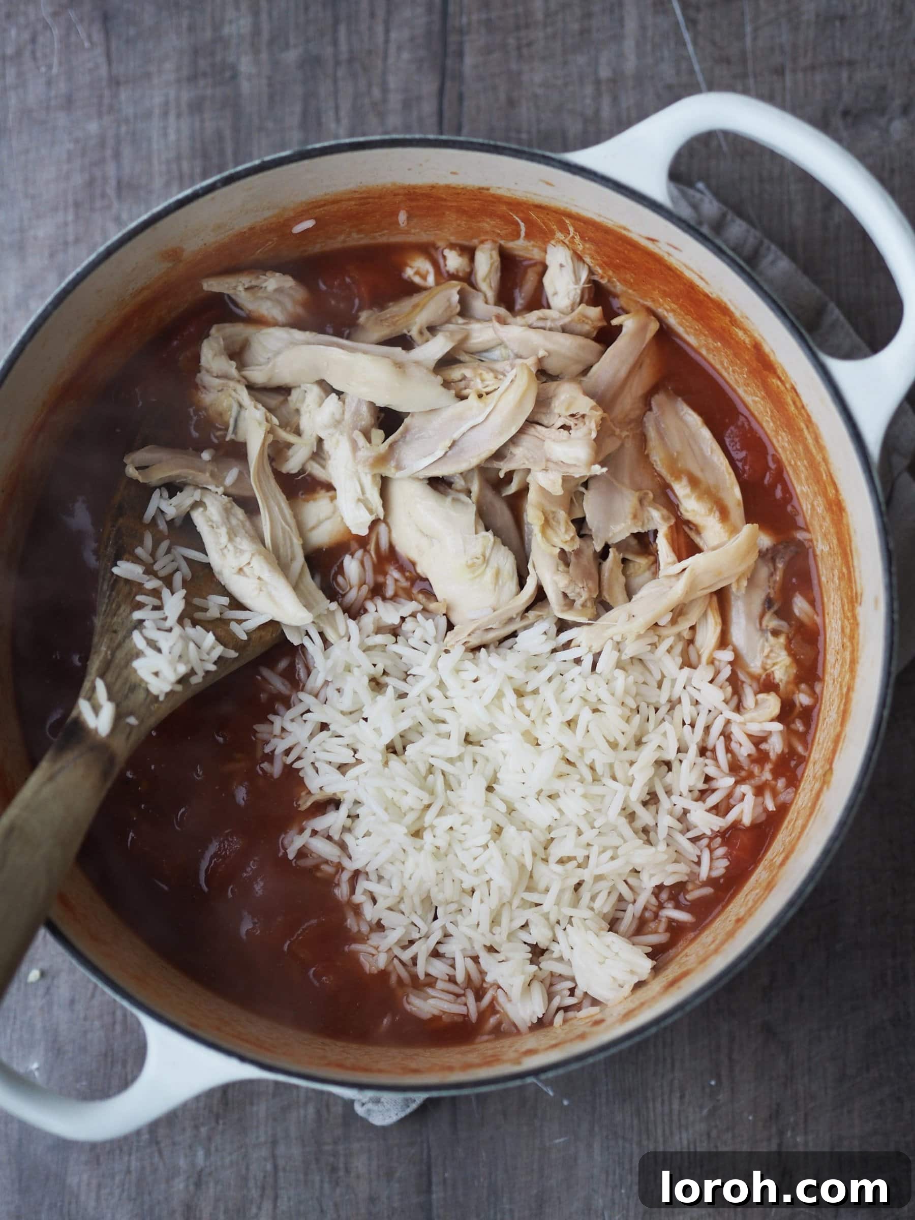 Adding shredded roast turkey and cooked rice to the simmering soup broth in a large pot.