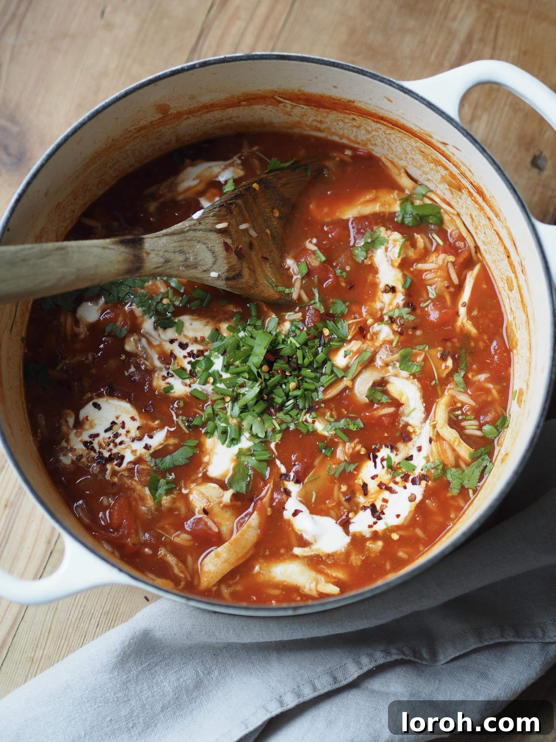 Adding a vibrant handful of fresh herbs and a squeeze of lemon juice to the finished Turkey and Rice Soup in a pot.