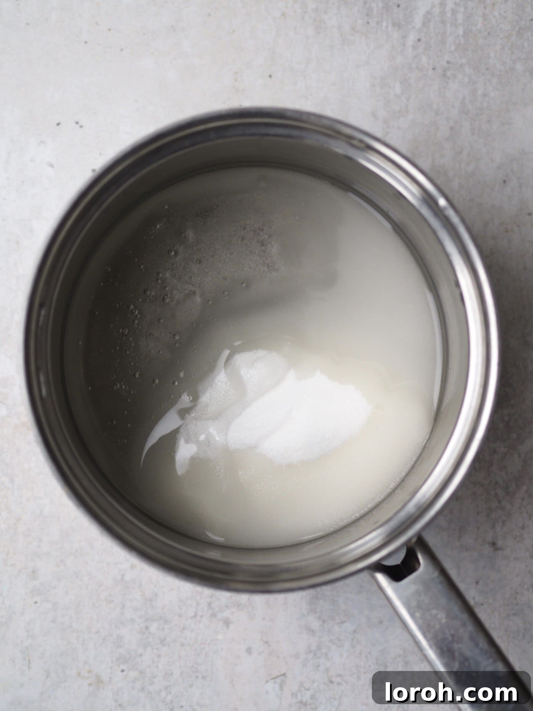 Adding caster sugar and liquid glucose to a saucepan with water to create the sugar syrup.