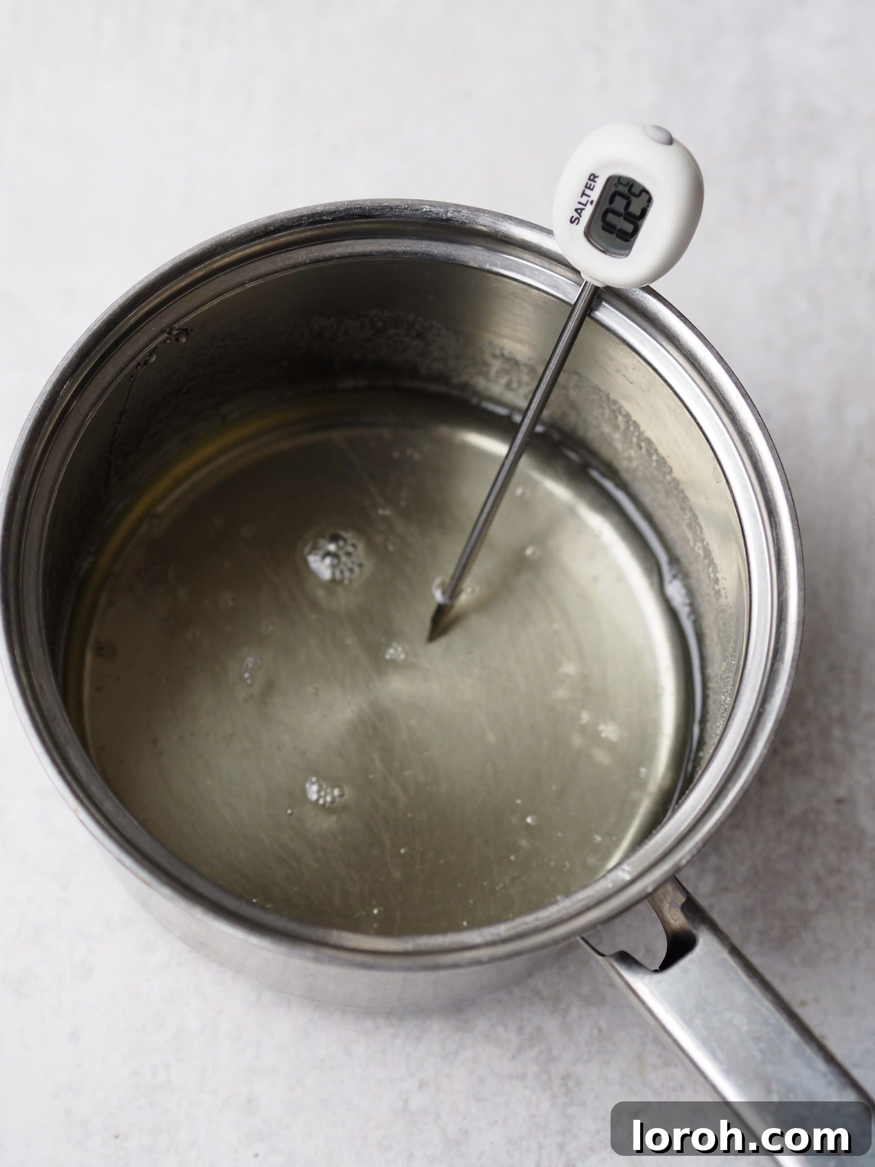 A sugar thermometer submerged in actively bubbling sugar syrup to precisely monitor its temperature.