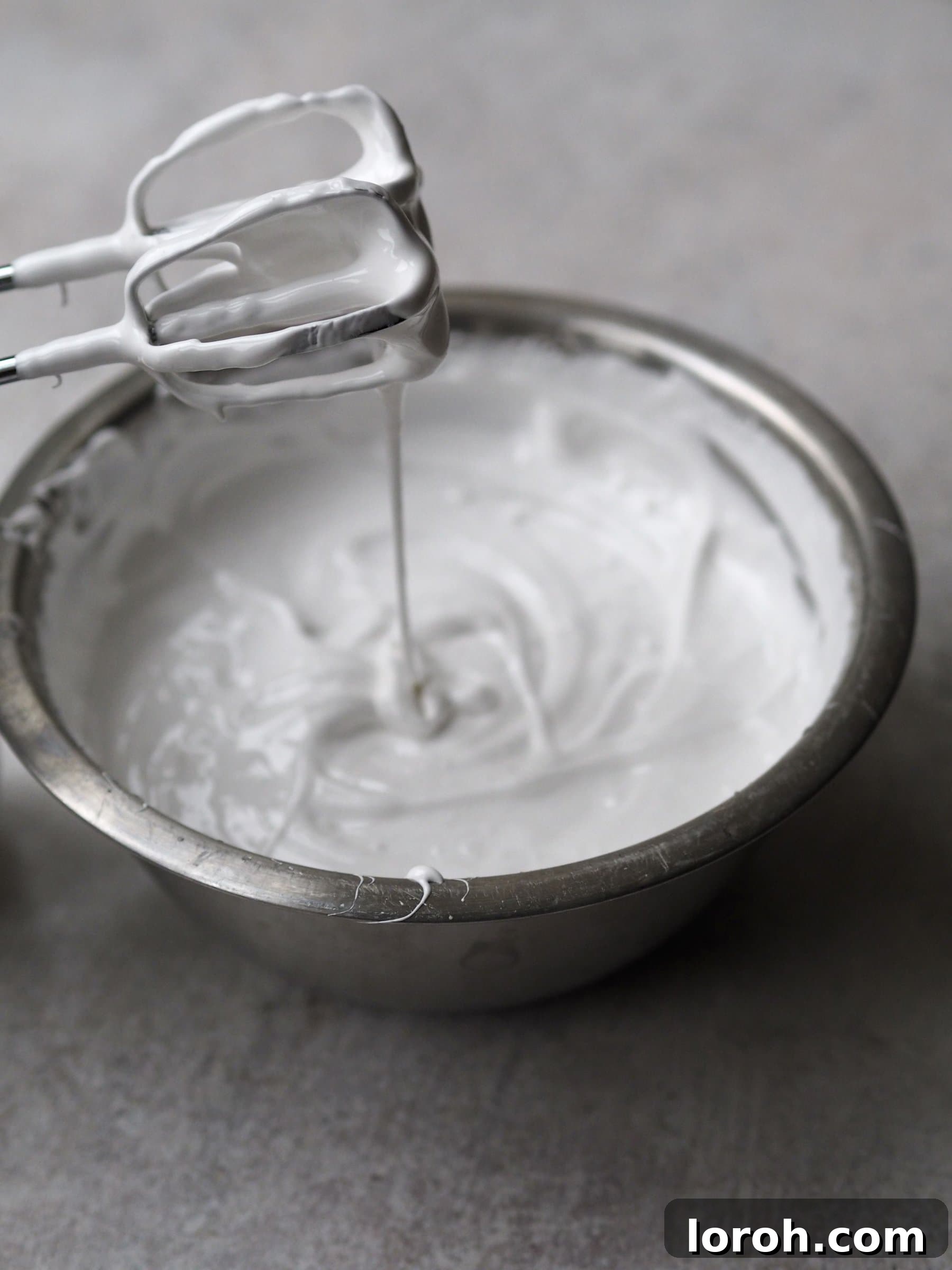 The marshmallow mixture transforming into a thick, glossy, white, meringue-like consistency after whisking.