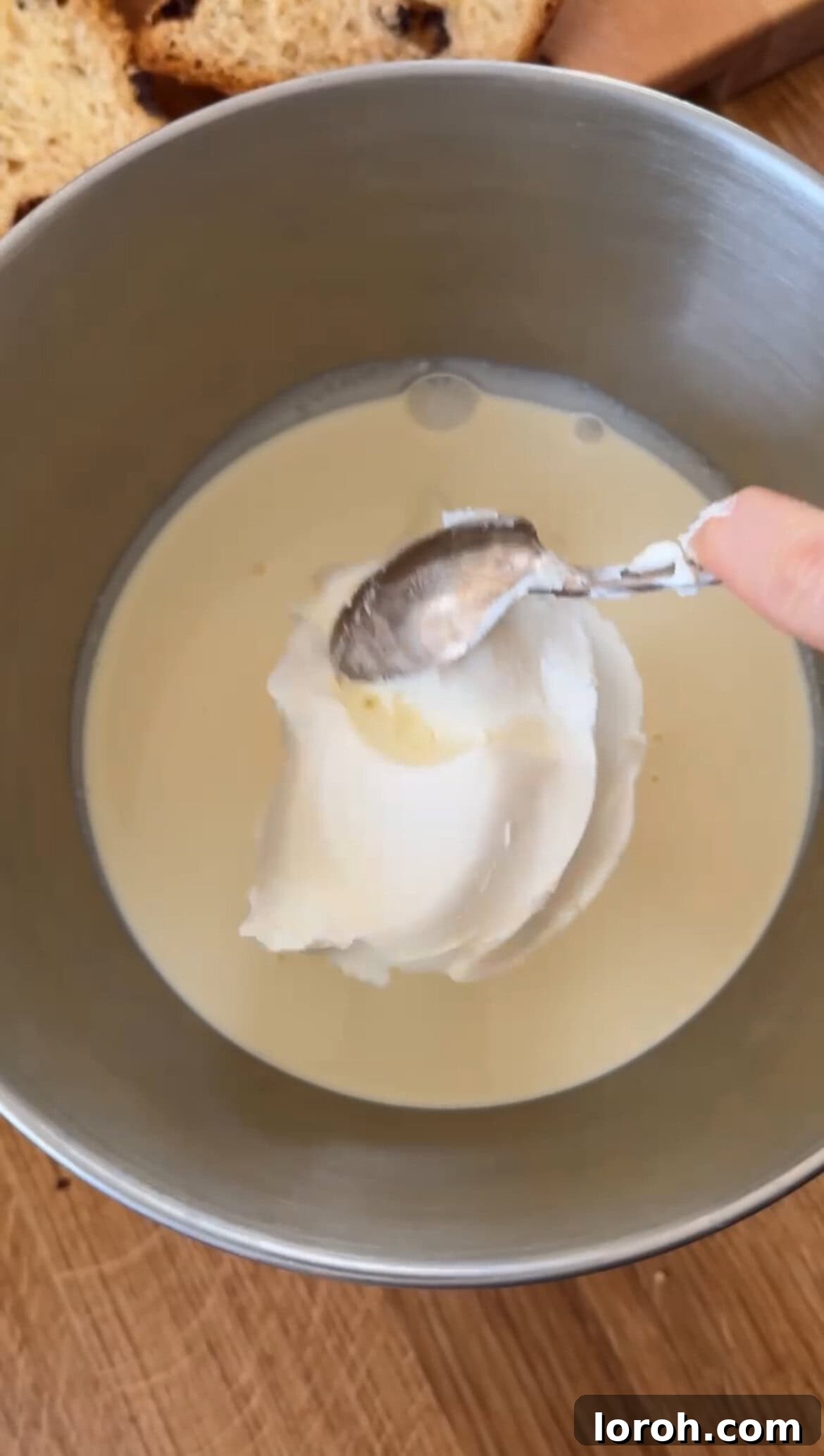 Adding mascarpone to double cream in a mixing bowl.