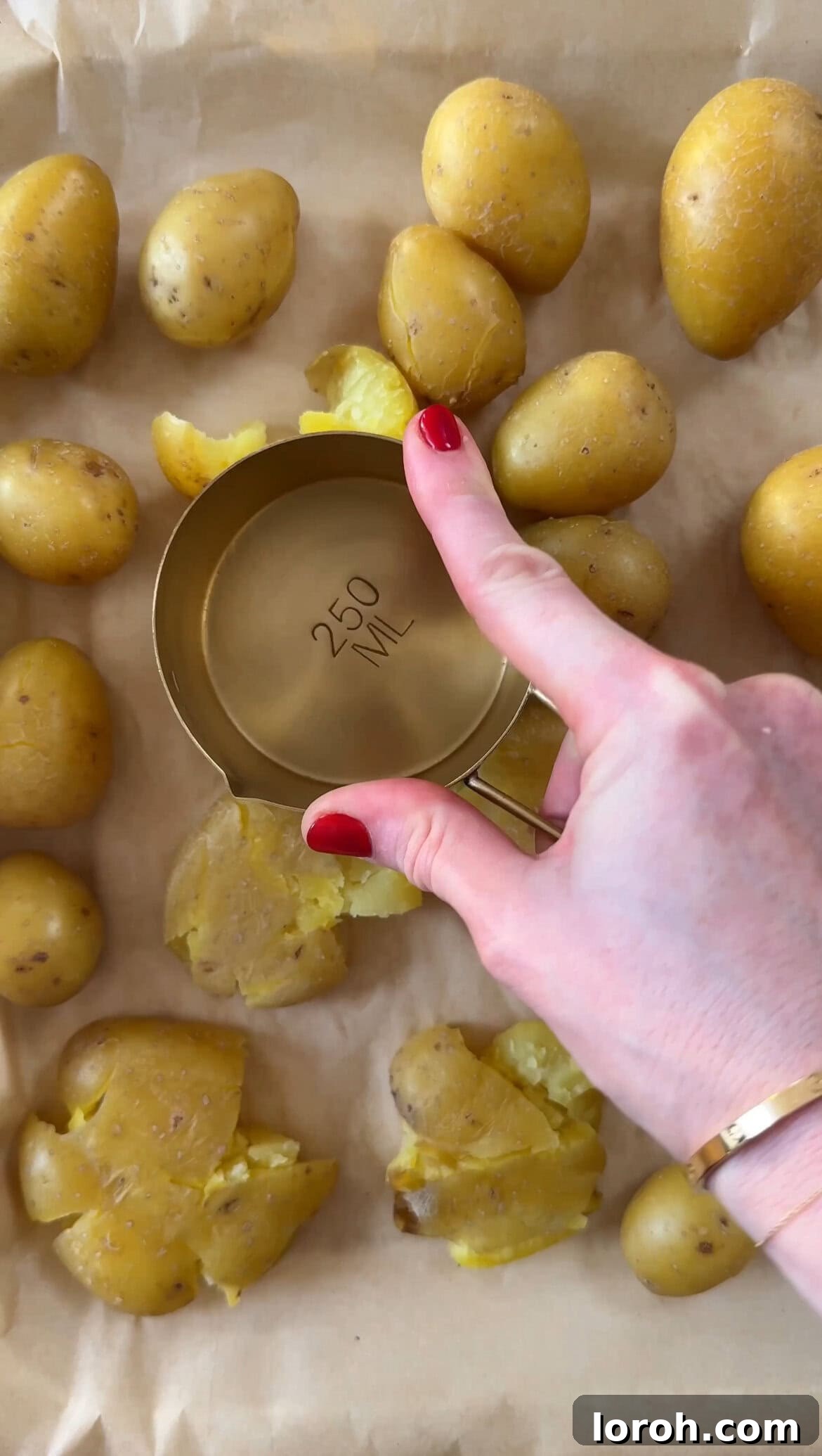 Smashed baby potatoes flattened on a baking sheet, seasoned with salt and pepper.