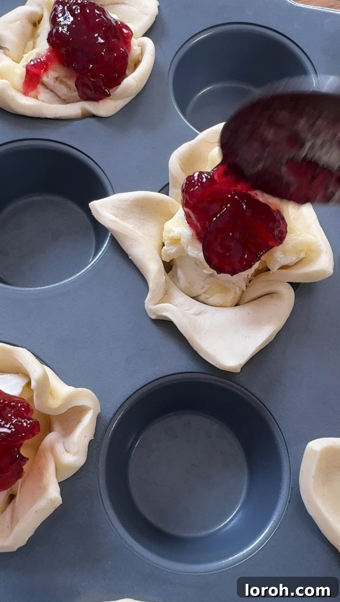 Golden Flaky Brie Bites 8 Cranberry sauce being added on top of the brie in each pastry cup.